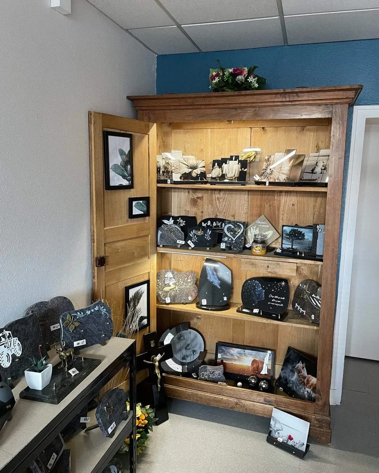 Armoire en bois authentique présentant des plaques funéraires et articles de marbrerie