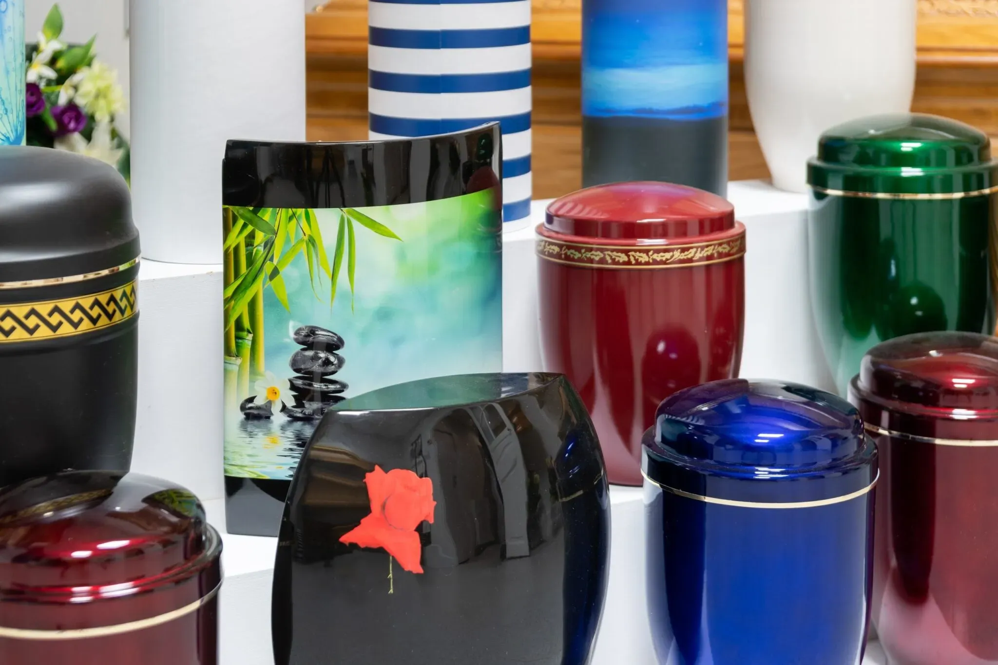 Collection d'urnes funéraires cinéraires de différentes couleurs et motifs exposées en vitrine
