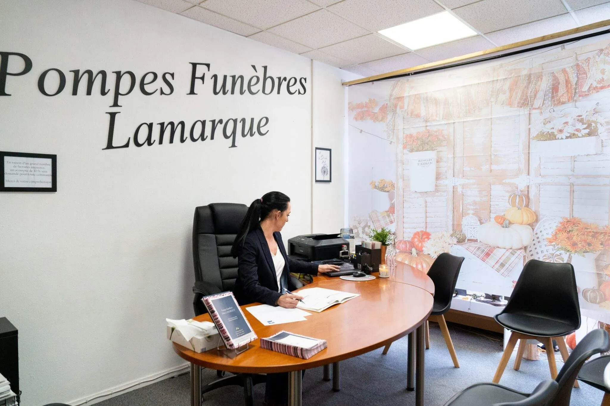 Conseillère funéraire assise à son bureau de reception de l'agence Pompes Funèbres Lamarque